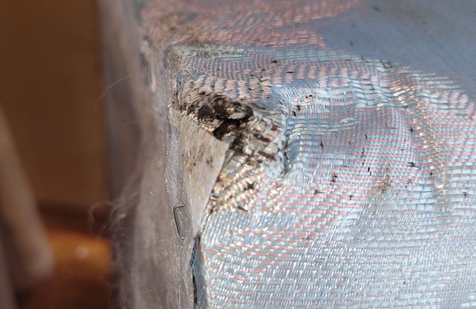 Gros plan sur un coin de matelas montrant des taches noires et des signes visibles d’infestation de punaises de lit.